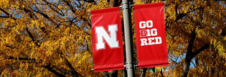 two flags with go big red and the unl "n" on a signpost